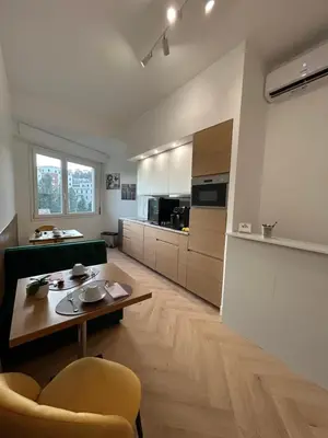 a living room with a table and a kitchen at GLhouse Roma Mazzini in Rome
