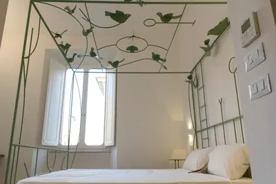 a bedroom with a metal canopy bed with leaves on the ceiling at La Casa Di Iulia in Rome