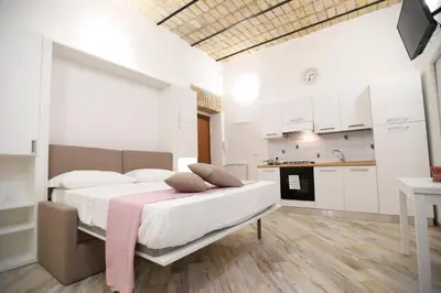 a bedroom with a large bed and a kitchen at Il Mattoncino - Colosseo in Rome