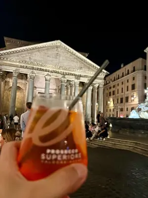 a hand holding a glass of beer in front of a building at Minerva Pantheon Suites in Rome