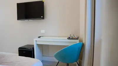 a blue chair sitting next to a desk with a television at Suites 215 Colosseum - Guesthouse in Rome