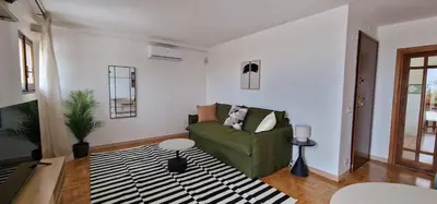 a living room with a green couch and a table at Nox Romana Apartment - Polyclinic Gemelli - Penthouse with Large Panoramic View Terrace in Rome