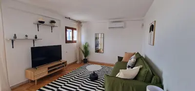 a living room with a green couch and a flat screen tv at Nox Romana Apartment - Polyclinic Gemelli - Penthouse with Large Panoramic View Terrace in Rome