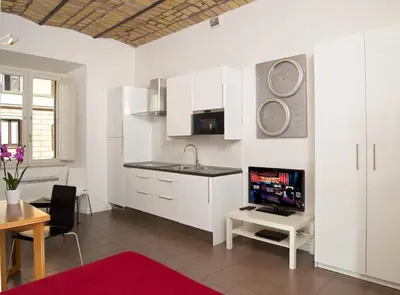 a kitchen with white cabinets and a sink and a table at Germanico Maxi in Rome