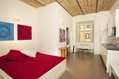 a bedroom with a red bed and a kitchen at Germanico Maxi in Rome