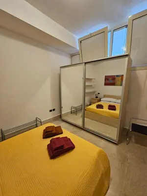 a bedroom with a yellow bed and a large mirror at SWEET HOME Porta Maggiore in Rome