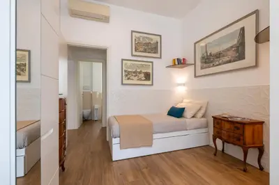 a white bedroom with a bed and a night stand at Clio Rome Suite 2 bedroom 2 bathroom apartment in Rome
