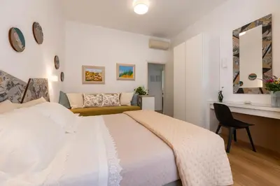 a bedroom with a large white bed and a chair at Clio Rome Suite 2 bedroom 2 bathroom apartment in Rome