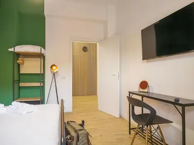 a room with a bed and a desk and a television at Relax e Style, Kairos, the house of quality time in Rome