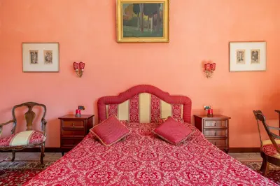 a bedroom with a red bed with two chairs at Residenza Episcopo Lipinsky 1902 in Rome