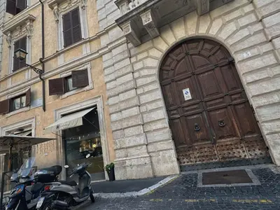 a scooter parked in front of a building with a large wooden door at Apt Aurea Luxury Pantheon View in Rome