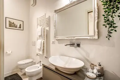 a white bathroom with a sink and a mirror at Orange Suites in Rome