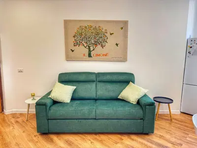 a green couch in a living room with a tree painting at Tito House in Rome