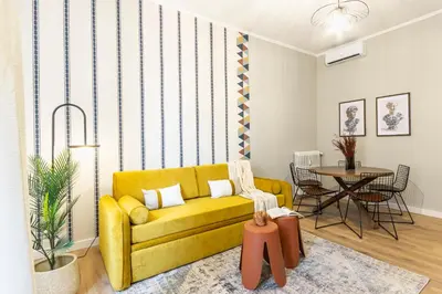 a living room with a yellow couch and a table at Collection39 Scipioni Luxury Apartment in Rome