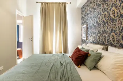 a bedroom with a bed with a blue wall at Collection39 Scipioni Luxury Apartment in Rome