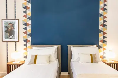 two beds in a room with a blue wall at Collection39 Scipioni Luxury Apartment in Rome