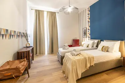 a bedroom with two beds and a blue wall at Collection39 Scipioni Luxury Apartment in Rome