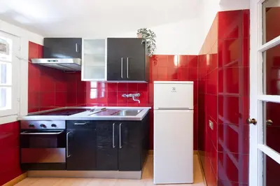 a red kitchen with a sink and a refrigerator at Casa Mia - Trastevere Rooftop Nest in Rome