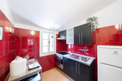 a red kitchen with black cabinets and a sink at Casa Mia - Trastevere Rooftop Nest in Rome