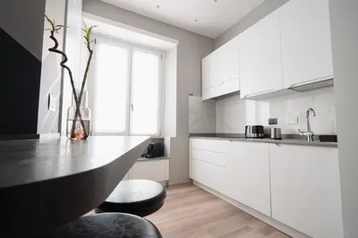 a kitchen with white cabinets and a black counter top at La Perla dell'Appia in Rome