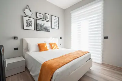 a white bedroom with a large bed with orange pillows at La Perla dell'Appia in Rome