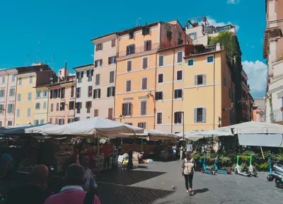 a woman walking through a market in front of buildings at Biscione Dream Campo de'Fiori in Rome