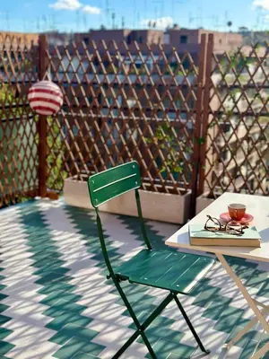 a green chair sitting next to a table with a book at Ai Parrocchetti, Loft con Terrazza Panoramica in Rome