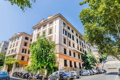 a tall white building on a city street with parked cars at APT ROME - Guest House Casini 6 Trastevere in Rome