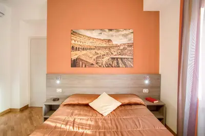 a bedroom with a bed with an orange wall at Vatican Rooms Cipro in Rome