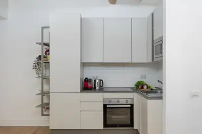 a kitchen with white cabinets and a stove at iFlat Monti Charming & Cozy Apt by the Colosseum in Rome