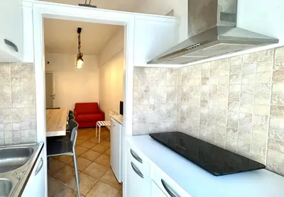 a kitchen with white cabinets and a red couch at Irpinia 19 Guest House in Rome
