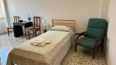 a bedroom with a bed and a chair and a table at Casa per Ferie Eden Cusmano in Rome