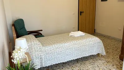 a bedroom with a bed and a chair and flowers at Casa per Ferie Eden Cusmano in Rome