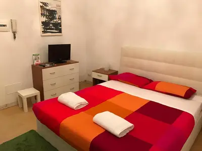 a bedroom with a colorful bed with a dresser and a television at Great studio near Coliseum in Rome