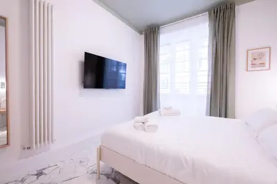 a white bedroom with a bed and a tv at Le Dimore del Duca in Rome
