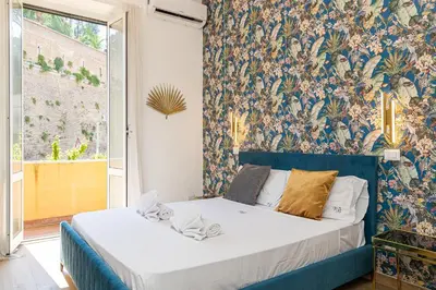 a bedroom with a blue bed with a floral wallpaper at Vatican Walls Apartment in Rome