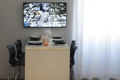 a white table with chairs and a tv on a wall at App Leoncino Design Apartment in Rome in Rome