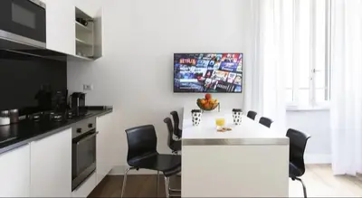 a kitchen with a white counter and black chairs at App Leoncino Design Apartment in Rome in Rome