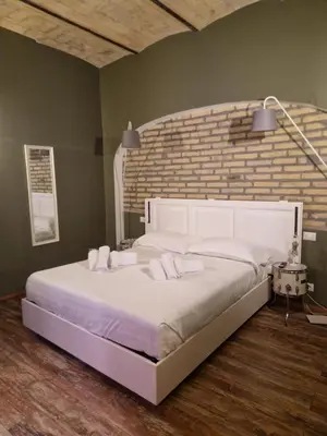 a large white bed in a bedroom with a brick wall at FCR Rome Apartments Sweet Nest of Love in Rome
