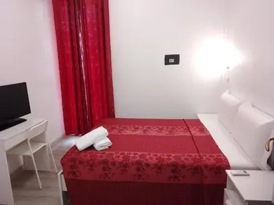 a small room with a red bed and a television at Euromoon in Rome