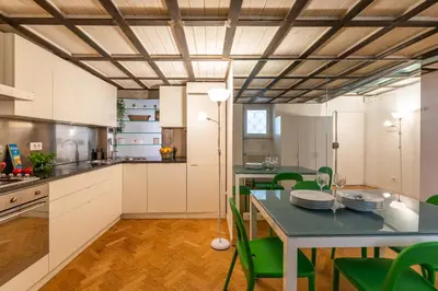 a kitchen with white cabinets and a table with green chairs at Navona award Collection in Rome