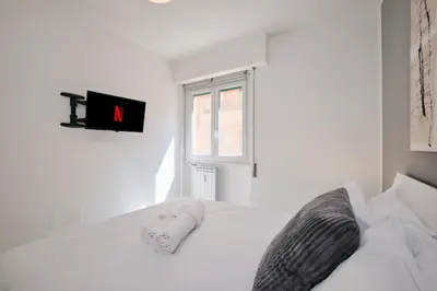 a white bedroom with a large white bed and a window at Apt at Tiburtina Station Free WiFi e Netflix in Rome