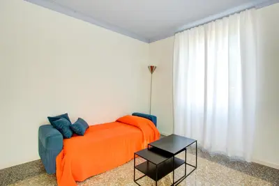 a bedroom with a bed with an orange blanket and a table at Casa Chiro 79 in Rome