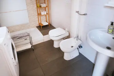 a white bathroom with a toilet and a sink at Charming 3-Guest Apt in San Giovanni Landmark in Rome
