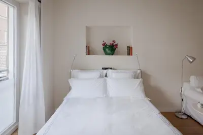 a white bed with white pillows in a bedroom at Tiber Island View - Trastevere, Campo de' Fiori in Rome