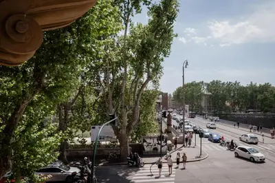 a busy city street with cars and people and trees at Tiber Island View - Trastevere, Campo de' Fiori in Rome