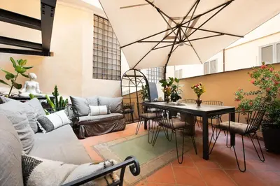 a patio with a table and chairs and a large umbrella at Idyllia - Luxury home with terrace in Rome