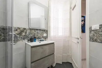 a white bathroom with a sink and a mirror at Appartamento vicolo Savelli in Rome