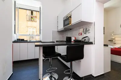 a kitchen with white cabinets and a black counter top at Casetta di quartiere Roma in Rome