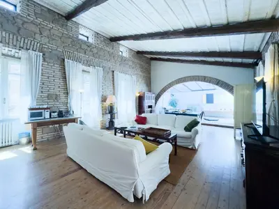 a living room with white furniture and a brick wall at The Loft Boutique Apartment Vatican Museum in Rome